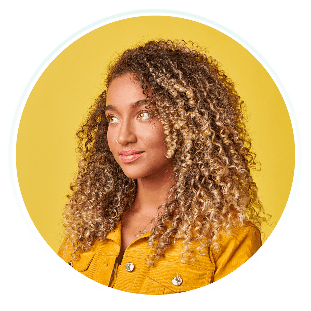 A young woman with curly hair, radiating positivity and confidence.