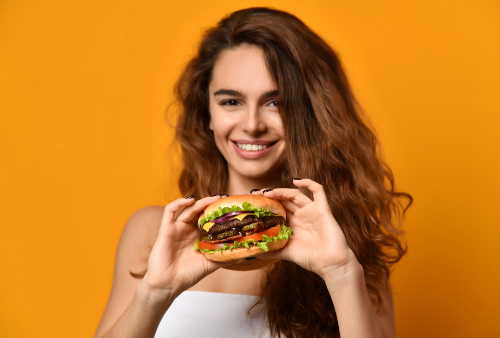 A woman is posing with the large size burger