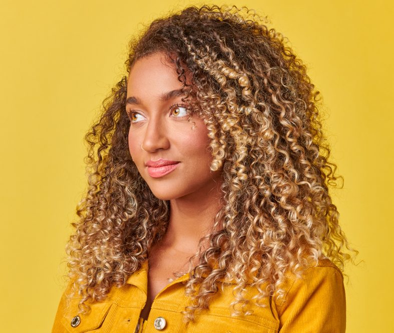 This image shows a curly hair girl who is happy and smilling