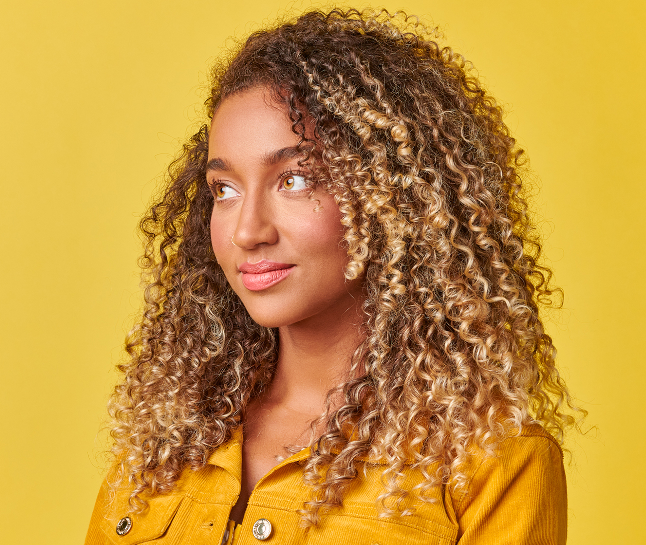 A young woman with curly hair, radiating positivity and confidence.